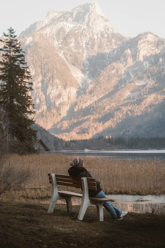 A person relaxes on a bench overlooking a serene mountain lake in Eisenerz, Austria.